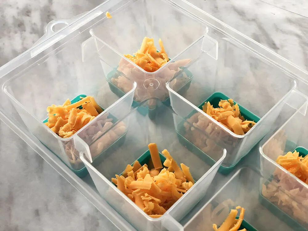 shredded cheddar cheese in the bottom of an ice cube tray for making cheeseburger dog treats