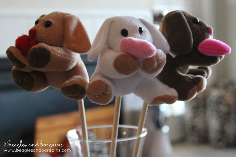 three plush toy dogs holding hearts on sticks to be made into a DIY Valentine's Day gift for dog lovers