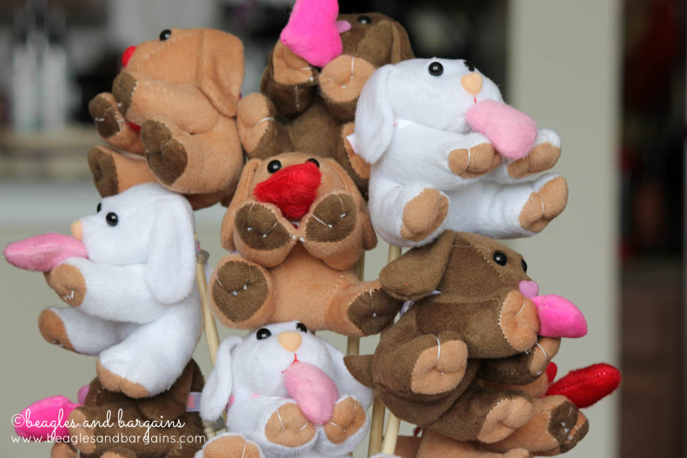 Close up photo pf plush toy dogs holding heats on sticks being made into a DIY Valentine's Day Bouquet