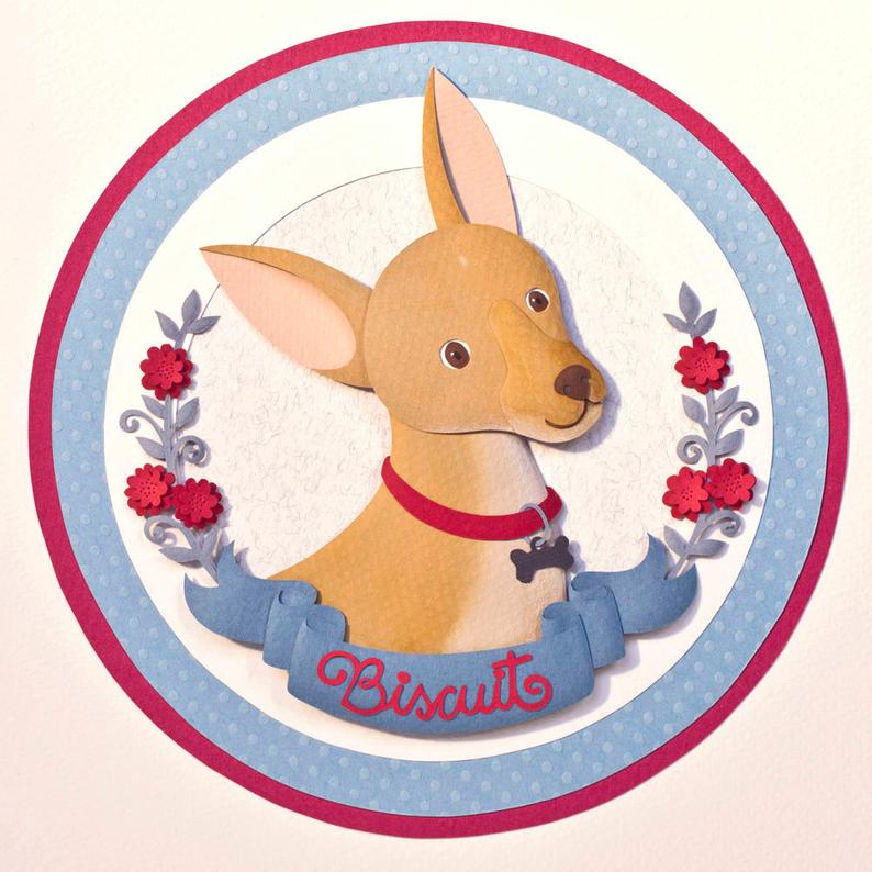 Circles of cards stock in red and blue surround a dog portrait made from pieces of layered paper showing a golden coloured chihuahua