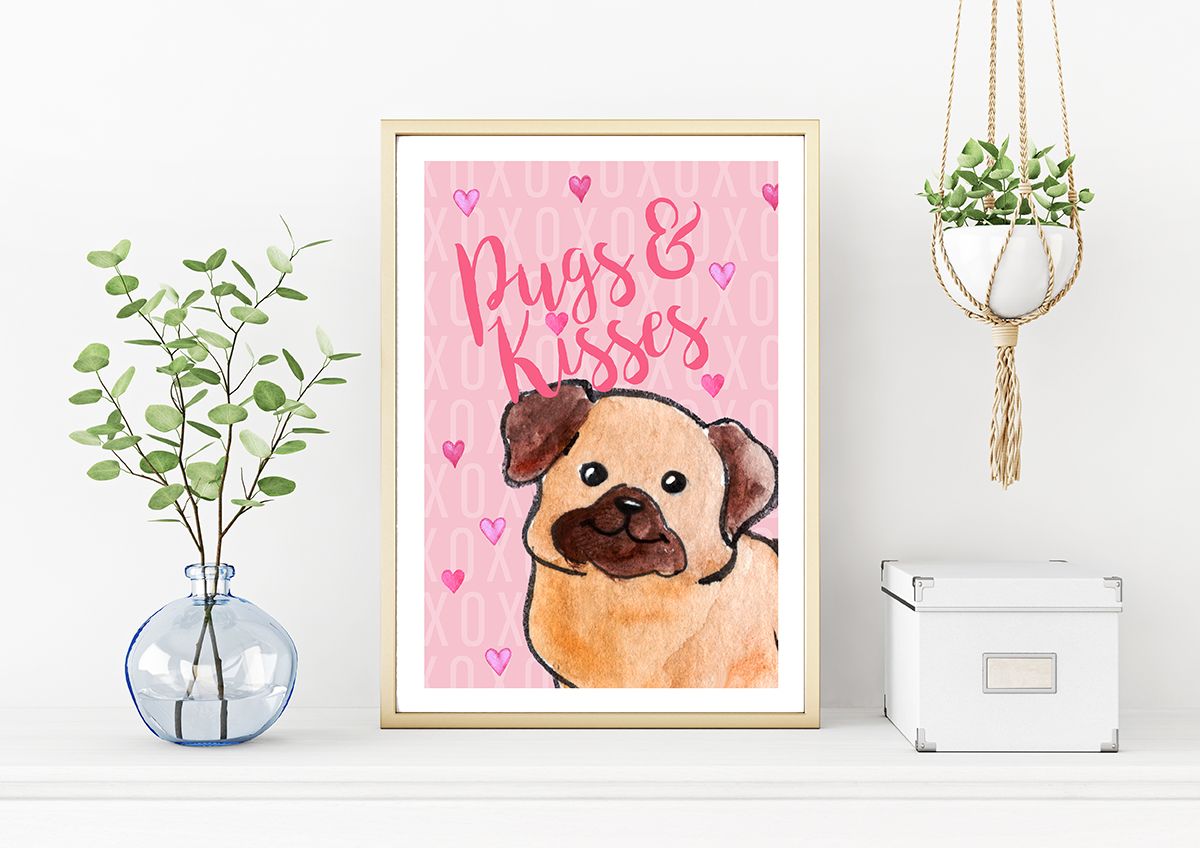 A vertical gold metal frame on the table with plants in blue vase and hanging macrame pot. In the frame is a free printable art piecec with a pink background and a watercolour pug on it. Text says: Pugs & Kisses.