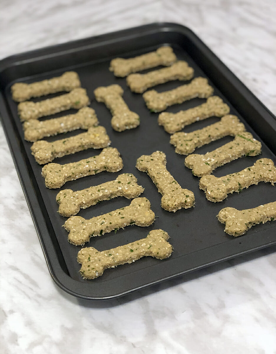bone shaped chicken dog treats ready to be baked on a sheet pan