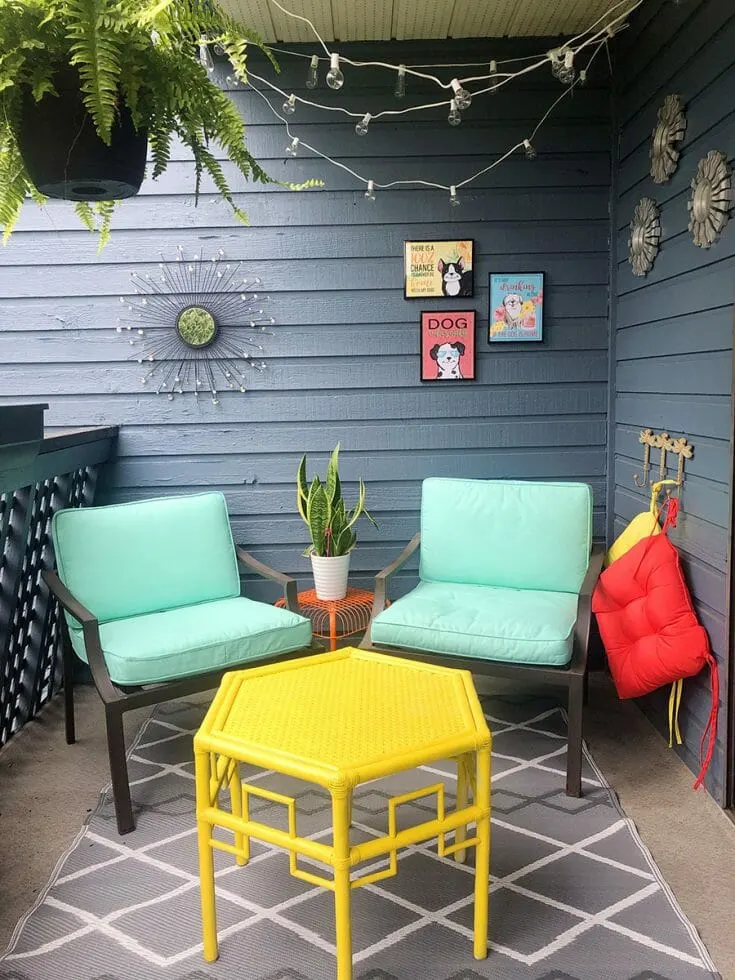 a brightly coloured patio with comfy teal chairs, a bright yellow octagon art deco table and printable dog art in black frames on the wall