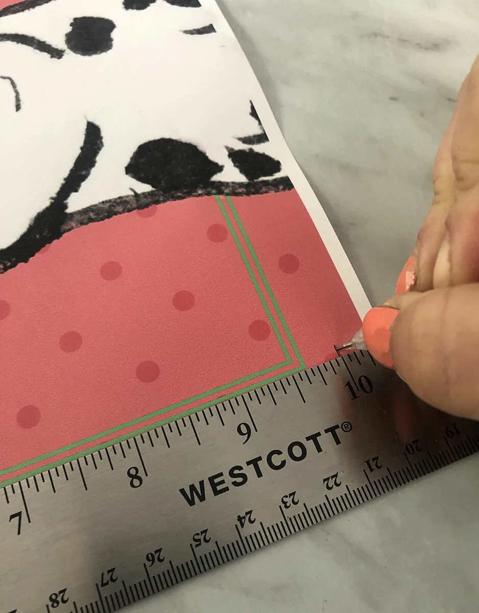 a piece of free printable summer dog art sits on a marble table with a metal ruler measuring where to cut