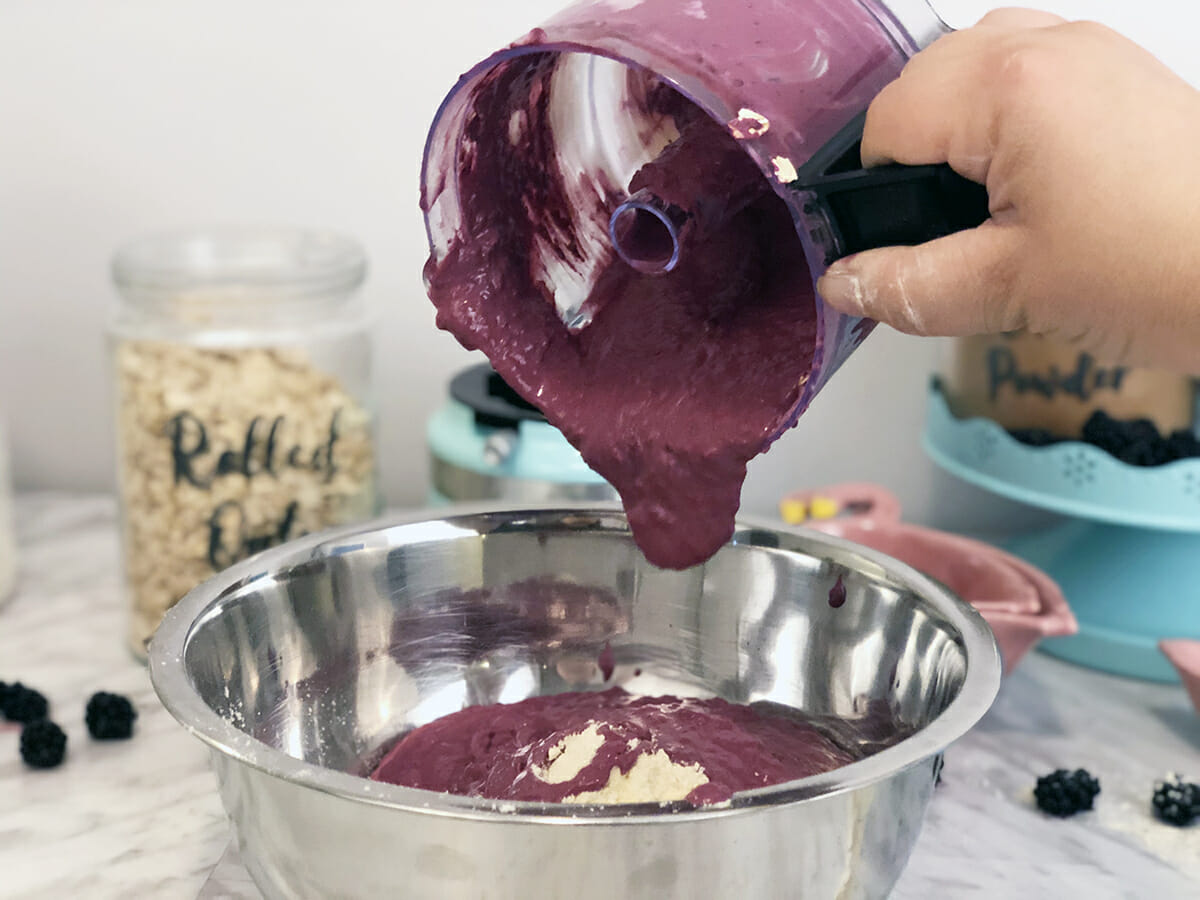 pouring blackberry puree into a bowl of dog treat mix