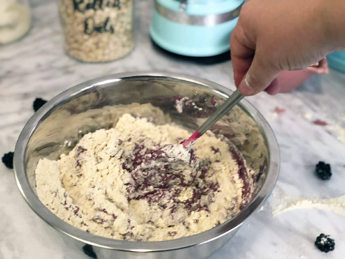 Stirring together the dough for a blackberry dog cookie with a spatula