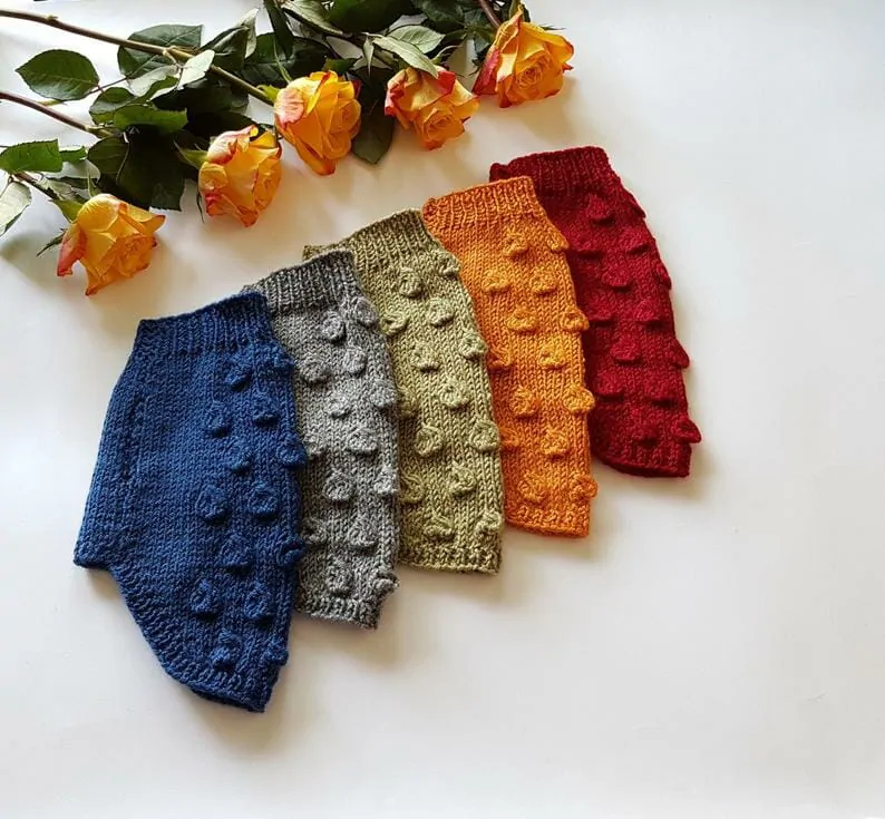 A fall toned rainbow of bobble knit dog sweaters from left to right in navy, grey, moss, pumpkin & maple leaf
